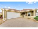Charming single-story home showcasing a large driveway, attached two-car garage and covered front entrance at 832 Parrish Pl, The Villages, FL 32163
