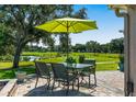 Outdoor patio area with an umbrella-covered table and chairs overlooking the golf course and lake at 9059 Se 177Th Grassmere St, The Villages, FL 32162