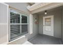 Inviting front entrance featuring a decorative door with sidelight, shuttered window, and a charming covered porch at 997 Oscar Ln, The Villages, FL 32162