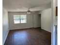 Bright living room featuring wood-look flooring, a ceiling fan, and natural light from a large window at 1109 Willow Ct, Tavares, FL 32778