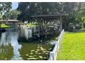 Dock and canal-side view with a wooden dock and covered seating area, and lush green landscaping at 11812 Watts Ct, Tavares, FL 32778