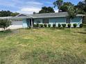 Single-story home with blue siding, a green lawn, and some landscaping and trees at 11812 Watts Ct, Tavares, FL 32778