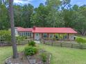 Charming single-story home featuring a red roof, shutters, landscaped front yard and a rustic wooden fence at 12288 Sw 35Th Dr, Webster, FL 33597