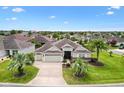Inviting single-story home featuring a three-car garage, beautiful landscaping, and a well-manicured lawn at 1376 Birdsong Pl, The Villages, FL 32163