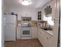 Bright kitchen features white cabinets, appliances, and a tile floor at 146 Hibiscus Way, Leesburg, FL 34748