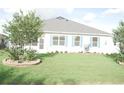 Back yard with lush green lawn and blue shuttered windows at 1676 Van Buren Way, The Villages, FL 32162