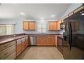 Bright kitchen with stainless steel dishwasher and black appliances, paired with warm, wood-toned cabinets at 16827 Se 92Nd Lance Ct, The Villages, FL 32162