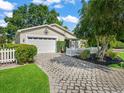 Charming home features a well-manicured lawn, stone paver driveway, and a white picket fence at 17324 Se 82Nd Pecan Ter, The Villages, FL 32162