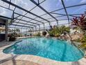 Screened-in pool with lush landscaping, rock waterfall feature, and clear turquoise water invites relaxation at 1861 Remembrance Ave, St Cloud, FL 34769