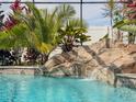 Close-up of a pool with rock waterfall, lush tropical foliage, and clear turquoise water at 1861 Remembrance Ave, St Cloud, FL 34769