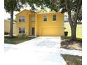 Yellow two-story home featuring a front yard with mature trees and an attached two-car garage at 2007 Country Brook Ave, Clermont, FL 34711