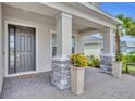 Covered front porch with brick columns, gray door and a neatly tiled floor surface at 2147 Timber Creek Ln, Clermont, FL 34715