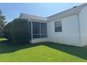 View of the home's rear exterior featuring a screened-in porch and a well-manicured lawn at 2530 Hanlon Ter, The Villages, FL 32162