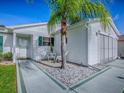 Close up of the front exterior with a palm tree, decorative rocks, and light-colored siding, presenting a clean, inviting entrance at 2799 Privada Dr, The Villages, FL 32162