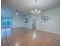 Spacious living room featuring wood floors, neutral walls, chandelier, ceiling fan, and a sliding door to the screened patio at 2799 Privada Dr, The Villages, FL 32162