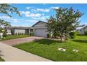A charming home with a brick driveway and lush lawn, shaded by a blossoming tree at 29810 Anahid Dr, Leesburg, FL 34748