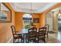 Elegant dining room featuring warm wall colors, decorative chandelier, and views of the outdoors at 34231 Shadewood Cir, Leesburg, FL 34788