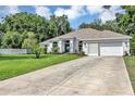 Wide driveway leading to a well-manicured lawn and a charming home with a classic white exterior at 34231 Shadewood Cir, Leesburg, FL 34788