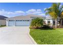 Charming home featuring a three-car garage, light-blue exterior, well-manicured lawn, and decorative driveway at 4878 Chitty Chatty Run, The Villages, FL 32163