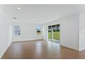 Bright living room with wood-look tile floors, modern recessed lighting, and sliding glass door at 5107 Marshelder St, Apopka, FL 32712