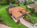 Beautiful aerial view of home showcasing terra cotta roof, green lawn, brick driveway, and mature landscaping at 5235 Island Terrace Ct, Lady Lake, FL 32159