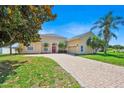 Charming, light yellow home with a brick driveway, red door, and well-maintained landscaping at 5556 Vintage View Blvd, Lakeland, FL 33812