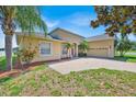 Charming, light yellow home with a brick driveway, red door, and well-maintained landscaping at 5556 Vintage View Blvd, Lakeland, FL 33812
