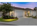 Charming home featuring a well-manicured lawn, attached garage, and inviting curb appeal at dusk at 579 Audrey Ln, The Villages, FL 32162
