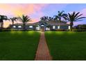 Charming single-story home featuring lush lawn, mature palms, and a welcoming brick pathway at dusk at 7350 Spring Mountain Ln, Yalaha, FL 34797
