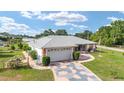 Well-maintained single-story home boasting a gray roof, patterned driveway, and a cozy screened-in front porch at 8850 Se 156Th St, Summerfield, FL 34491