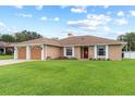 Inviting single-story home with a well-maintained lawn, two-car garage, and classic design at 1414 Cove Pl, Tavares, FL 32778