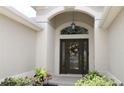 Elegant front entrance with a decorative wreath, transom window, and lush landscaping at 1553 Lynchburg Loop, The Villages, FL 32162