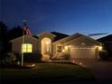 Inviting single-story home with landscape lighting and well-maintained lawn at dusk at 20936 Royal St Georges Ln, Leesburg, FL 34748