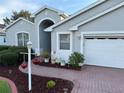 Charming single-story home featuring a brick driveway and landscaped yard with flowers at 20936 Royal St Georges Ln, Leesburg, FL 34748