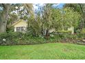 Landscaped front yard filled with mature shrubbery and trees surrounding the house with lush green grass at 24 Brigadoon Cir, Leesburg, FL 34788