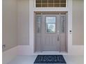 Close-up of the front door featuring decorative glass sidelights, secure lock, and a stylish welcome mat at 2954 Heiny Pl, The Villages, FL 32163