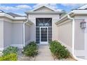 Inviting front entrance with a decorative white security door, lush landscaping, and charming curb appeal at 2954 Heiny Pl, The Villages, FL 32163