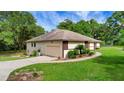 Captivating view of the home featuring a side-entry garage, lush lawn and detailed landscaping around the property at 39132 Grays Airport Rd, Lady Lake, FL 32159