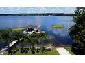 Scenic view of a private dock with boat lift, lounge chairs, and palm trees on a serene lake at 4634 Bigler Ln, Mount Dora, FL 32757