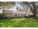 Well-maintained front yard with mature trees and stone accents on a single-story home at 500 Lake Forest Cir, Mount Dora, FL 32757