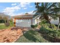 Inviting single-story home featuring a tile roof, red brick driveway, and a meticulously landscaped yard at 5046 Harbour Dr, Oxford, FL 34484