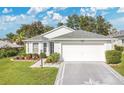Beautiful single-story home with a patterned driveway, well-manicured lawn, and mature landscaping at 5562 Charleston Avenue, Tavares, FL 32778