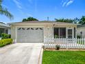 Home exterior with a garage, a screen porch, a white picket fence and a well-manicured lawn at 8195 Se 174Th Rowland St, The Villages, FL 32162