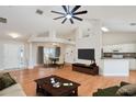 Open-concept living room showcasing wood floors, dining area, kitchen, and a large ceiling fan at 832 Willow Run St, Minneola, FL 34715