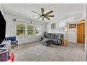 Cozy living room with neutral carpet, ceiling fan, and a large window overlooking the yard at 1 W Pierce Ave, Orlando, FL 32809