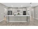 Modern kitchen with white cabinets, quartz countertops, stainless steel appliances, and wood-look tile flooring at 15954 Winding Bluff Dr, Montverde, FL 34756