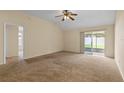Spacious carpeted living room with a ceiling fan, sliding glass doors leading to a patio, and neutral-colored walls at 1730 Dorset Dr, Mount Dora, FL 32757