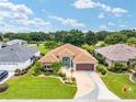Aerial shot of a well-kept single-story home with manicured lawns, decorative driveway, and colorful landscaping at 219 Carrera Dr, The Villages, FL 32159