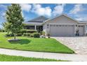 Well-maintained home featuring a lush green lawn and a paver driveway leading to a two-car garage at 26601 Otter Creek Ln, Leesburg, FL 34748