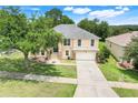 Lovely two-story home showcasing lush landscaping, mature trees, and a well-manicured lawn at 2745 Shearwater St, Clermont, FL 34711
